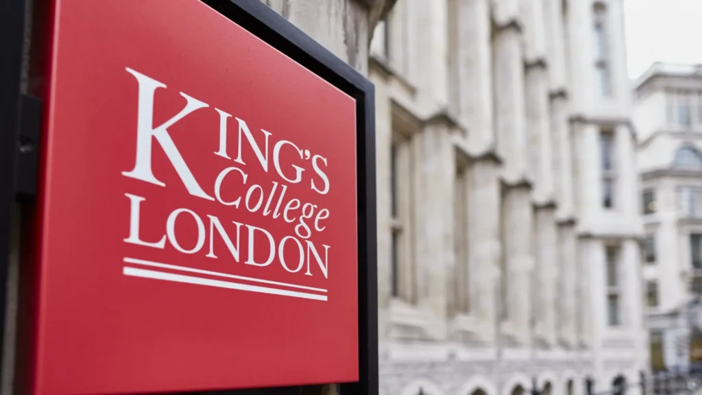 Red King’s College London sign mounted on a stone building with the university’s neoclassical façade in the background